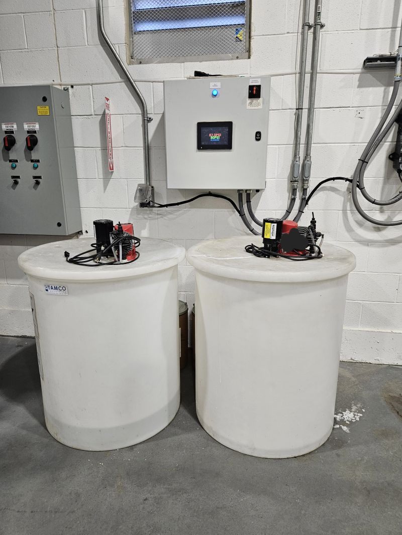 Bulk chemical feed tanks and a touchscreen control panel for a wastewater program, installed by Hoffman Water